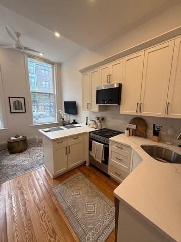 kitchen featuring a peninsula, dark wood-type flooring, light countertops, a sink, and appliances with stainless steel finishes