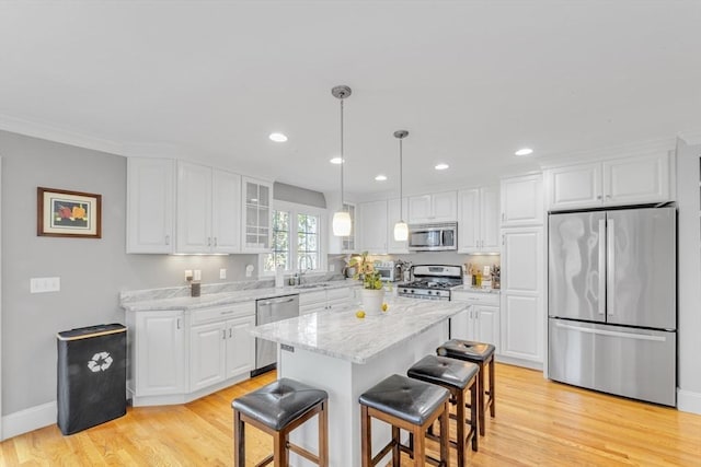 kitchen with stainless steel appliances, white cabinets, light wood-type flooring, a kitchen breakfast bar, and recessed lighting
