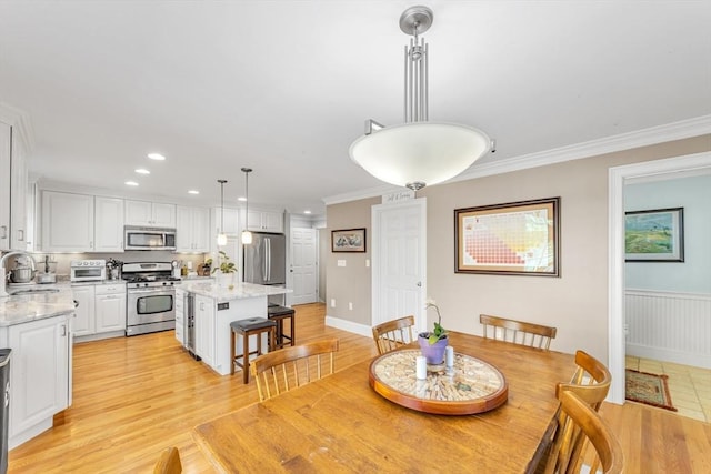 dining space featuring recessed lighting, ornamental molding, and light wood-style floors