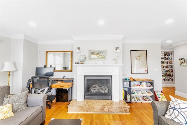 living room featuring wood finished floors, ornamental molding, a glass covered fireplace, recessed lighting, and baseboards