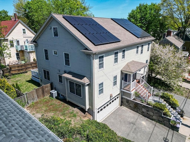 view of home's exterior featuring stairs, roof mounted solar panels, asphalt driveway, a garage, and a shingled roof