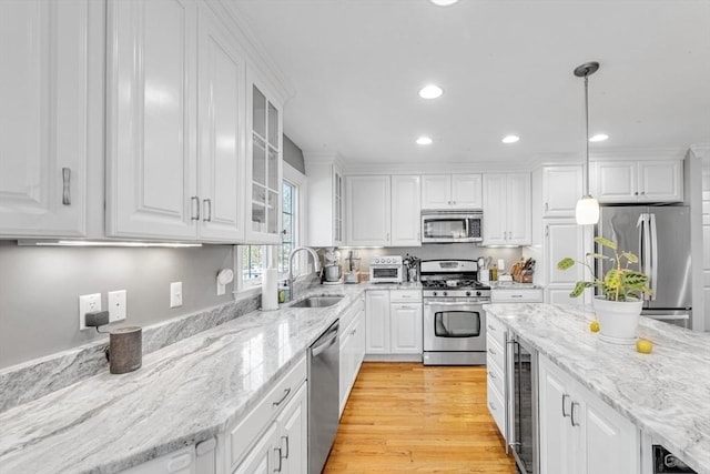 kitchen featuring stainless steel appliances, a sink, white cabinetry, recessed lighting, and decorative light fixtures