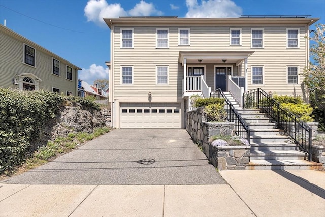 view of front facade featuring stairway, driveway, an attached garage, and covered porch