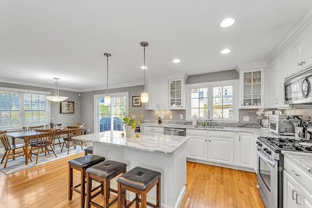 kitchen with appliances with stainless steel finishes, a sink, white cabinetry, a breakfast bar area, and recessed lighting