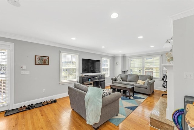 living area featuring healthy amount of natural light, ornamental molding, recessed lighting, light wood-style flooring, and baseboards