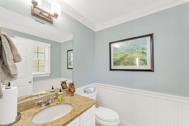 bathroom with a wainscoted wall, toilet, vanity, and ornamental molding