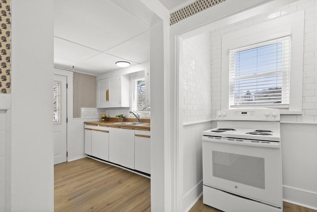 63 Adams St, Bourne, MA 02532 - kitchen featuring white cabinetry, white range with electric stovetop, a sink, and light wood finished floors