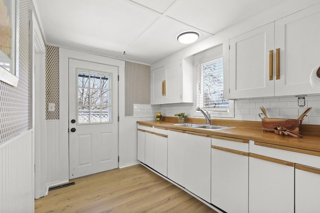 63 Adams St, Bourne, MA 02532 - kitchen featuring a sink, white cabinetry, backsplash, and a wealth of natural light