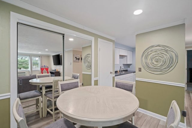 dining room with crown molding, light wood-style flooring, recessed lighting, and baseboards