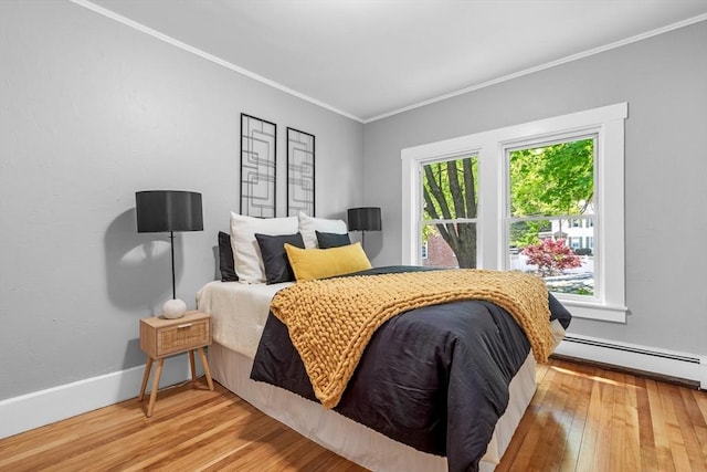 bedroom with a baseboard radiator, ornamental molding, wood finished floors, and baseboards