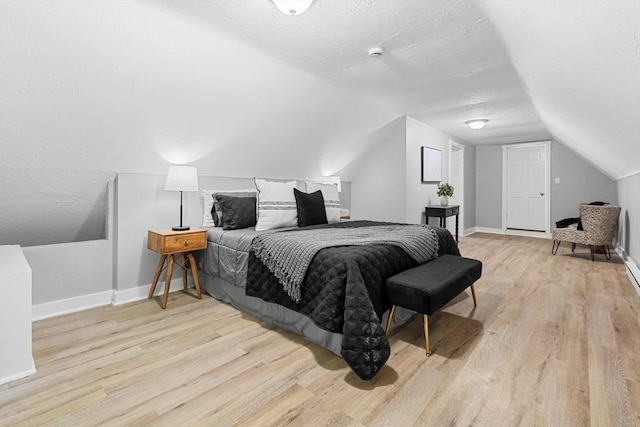 bedroom featuring wood finished floors, vaulted ceiling, and baseboards