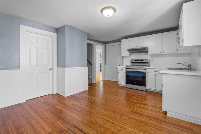 kitchen featuring stainless steel range with electric stovetop, a sink, light countertops, light wood-style floors, and a textured ceiling