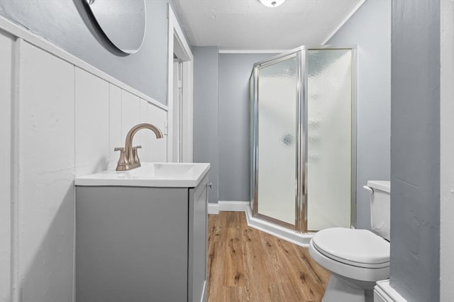 full bathroom featuring wood finished floors, a shower stall, toilet, and vanity