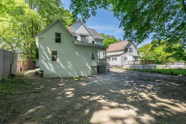 back of house featuring fence and a chimney