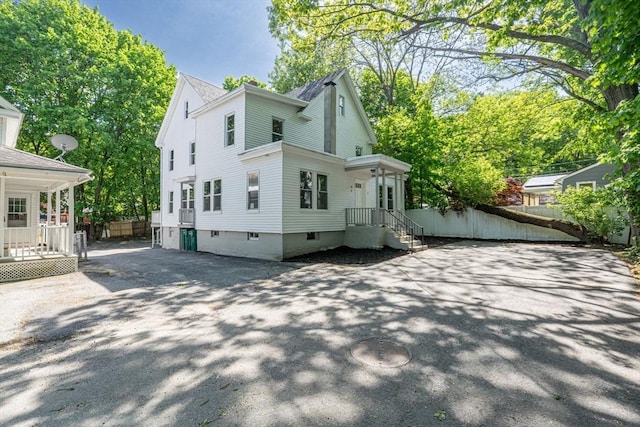 view of side of home featuring fence and asphalt driveway