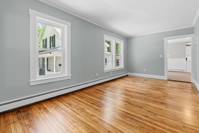 spare room with a baseboard heating unit, crown molding, light wood-style flooring, baseboard heating, and baseboards