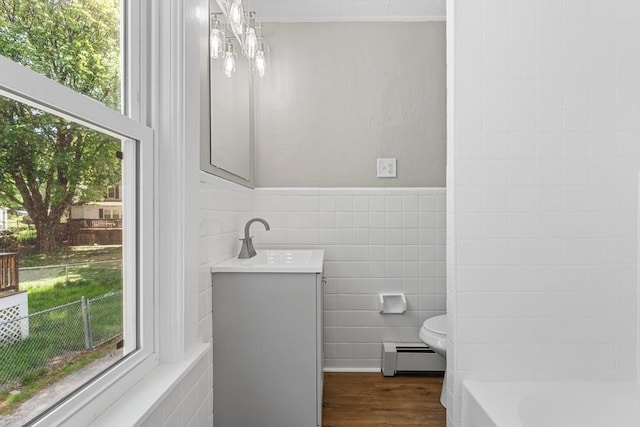full bath featuring baseboard heating, tile walls, plenty of natural light, wood finished floors, and vanity
