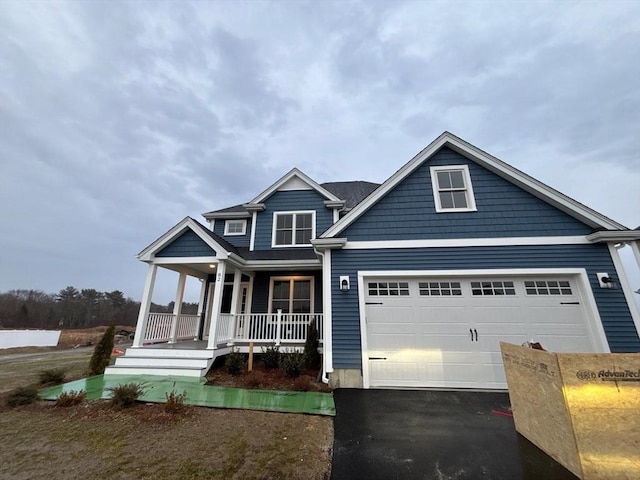 view of front of house featuring a porch, an attached garage, and aphalt driveway