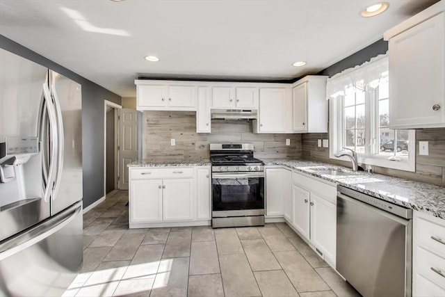 kitchen featuring stainless steel appliances, white cabinetry, sink, and light stone counters