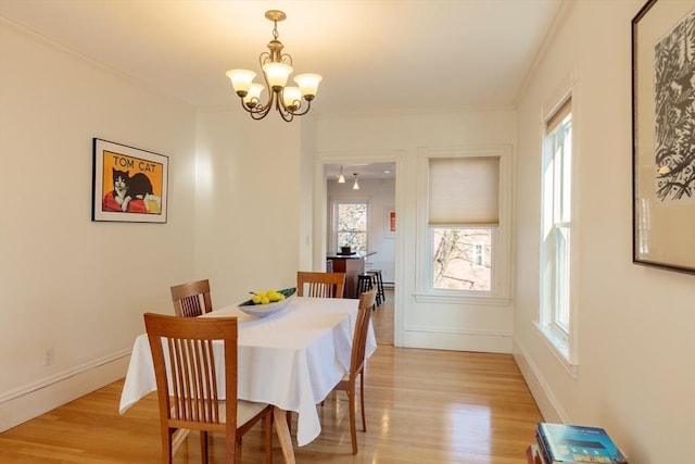 dining room featuring a chandelier, light wood-type flooring, and crown molding