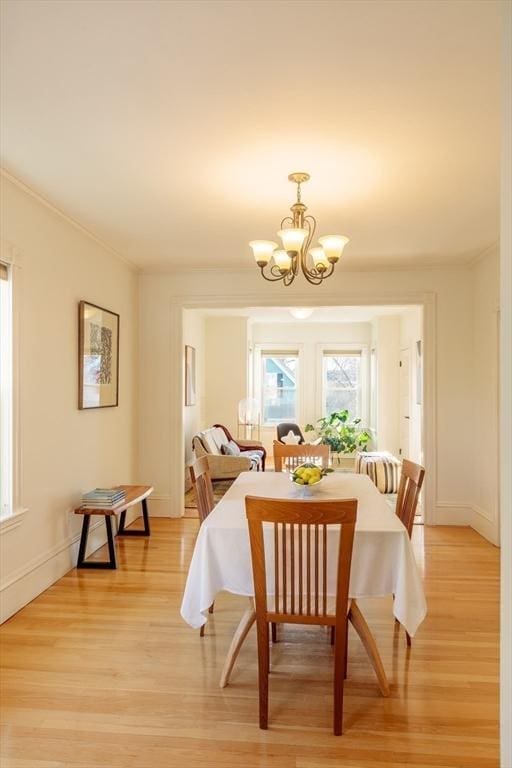 dining area with a chandelier, light wood-type flooring, and crown molding