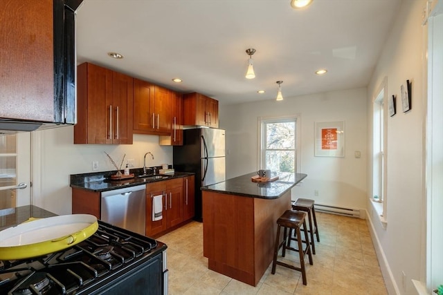 kitchen with appliances with stainless steel finishes, a kitchen breakfast bar, sink, a center island, and hanging light fixtures