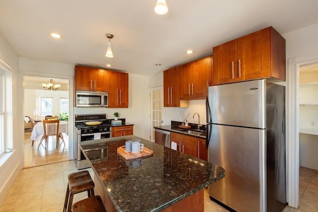 kitchen featuring sink, hanging light fixtures, a notable chandelier, a kitchen island, and stainless steel appliances