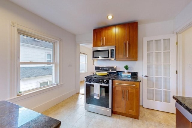 kitchen with dark stone countertops, light tile patterned floors, and stainless steel appliances