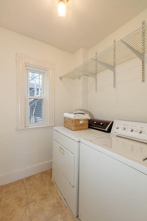 clothes washing area with light tile patterned floors and washer and dryer