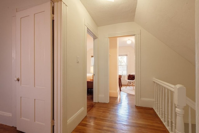 hall with vaulted ceiling and hardwood / wood-style flooring