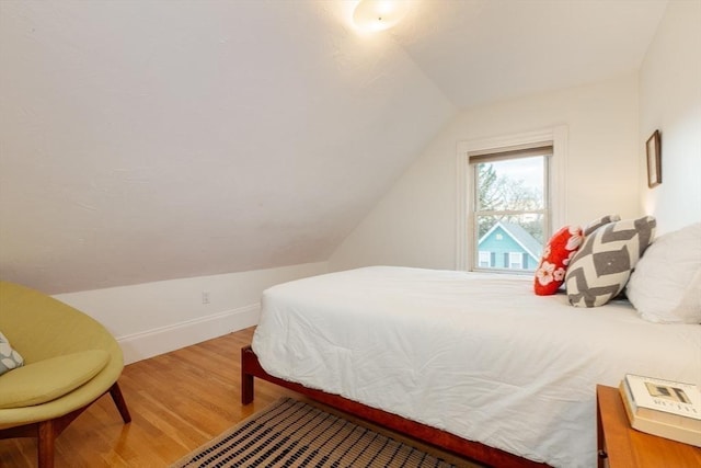 bedroom with hardwood / wood-style flooring and lofted ceiling