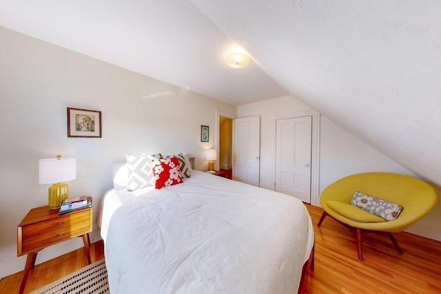 bedroom featuring a closet, hardwood / wood-style floors, and vaulted ceiling