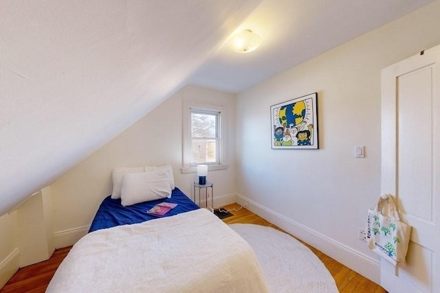 bedroom with vaulted ceiling and hardwood / wood-style flooring