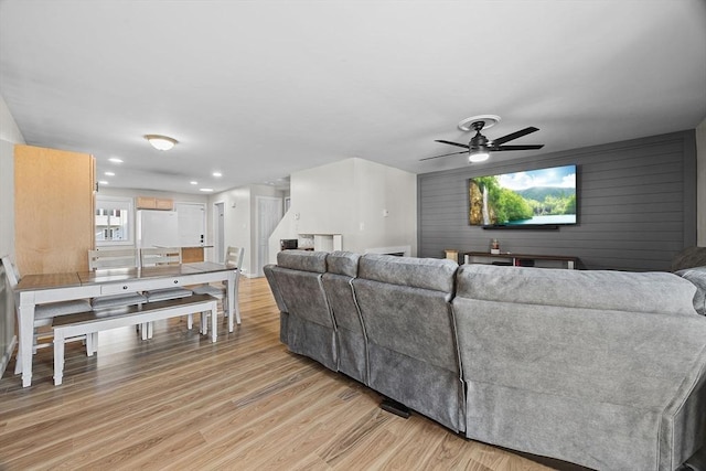 living room with recessed lighting, light wood-type flooring, wood walls, and a ceiling fan