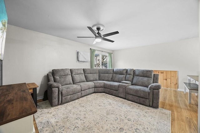 living area with baseboards, ceiling fan, and wood finished floors