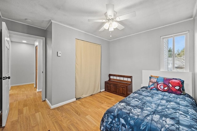 bedroom with a textured ceiling, baseboards, light wood-type flooring, and ornamental molding