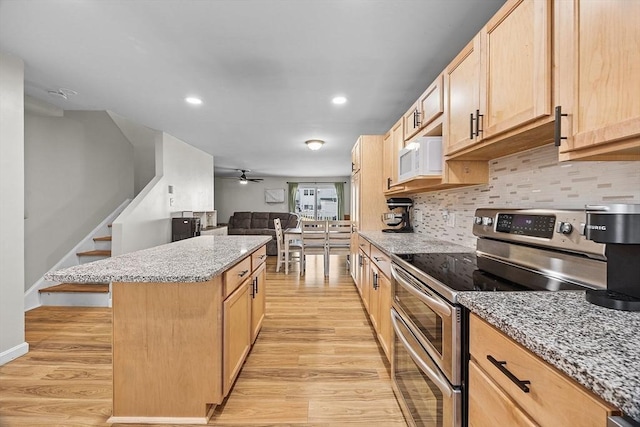 kitchen featuring backsplash, double oven range, a center island, and light wood-type flooring