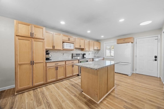 kitchen featuring a center island, light brown cabinetry, decorative backsplash, light wood-style flooring, and appliances with stainless steel finishes