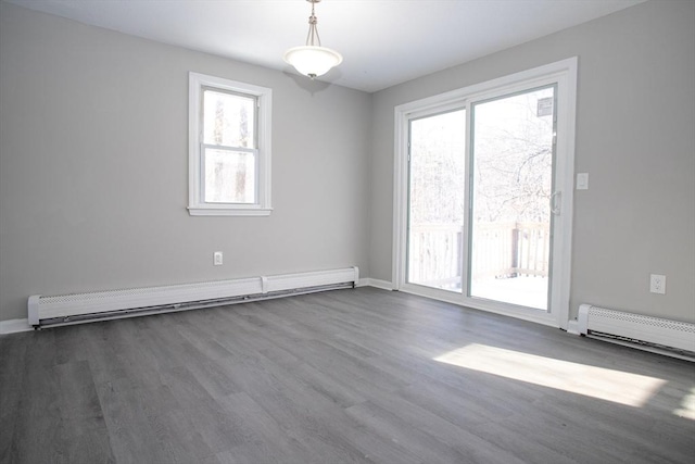 empty room with a baseboard radiator, baseboards, baseboard heating, and wood finished floors