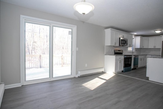 kitchen featuring backsplash, a baseboard radiator, stainless steel appliances, and a wealth of natural light