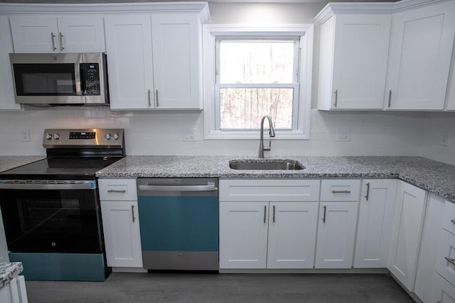 kitchen featuring white cabinetry, appliances with stainless steel finishes, decorative backsplash, and a sink