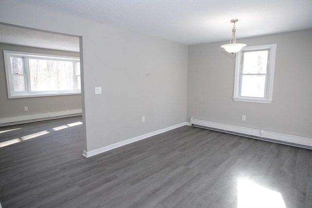 spare room featuring baseboards, a baseboard heating unit, and dark wood finished floors