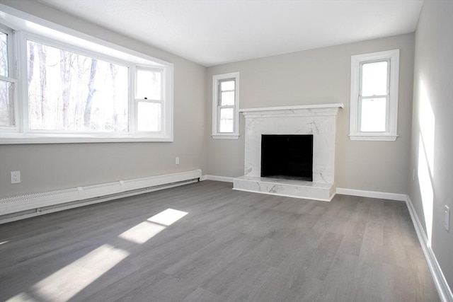 unfurnished living room with a premium fireplace, baseboards, baseboard heating, and wood finished floors