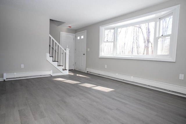 unfurnished living room featuring a baseboard radiator, stairs, baseboard heating, and wood finished floors