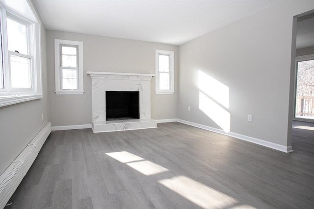 unfurnished living room featuring plenty of natural light, a baseboard radiator, a fireplace, and baseboards