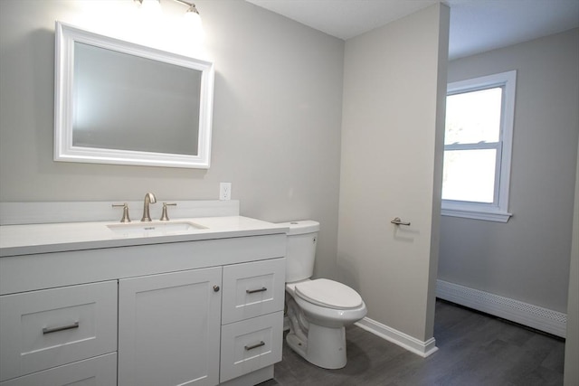 bathroom featuring baseboards, toilet, wood finished floors, vanity, and a baseboard heating unit