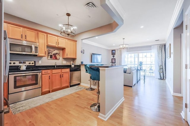 kitchen featuring open floor plan, stainless steel appliances, an inviting chandelier, and light wood-style flooring