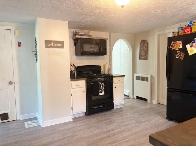 kitchen with black appliances, radiator heating unit, light hardwood / wood-style flooring, a textured ceiling, and white cabinetry