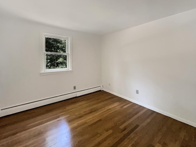 spare room featuring baseboards, a baseboard heating unit, and dark wood finished floors