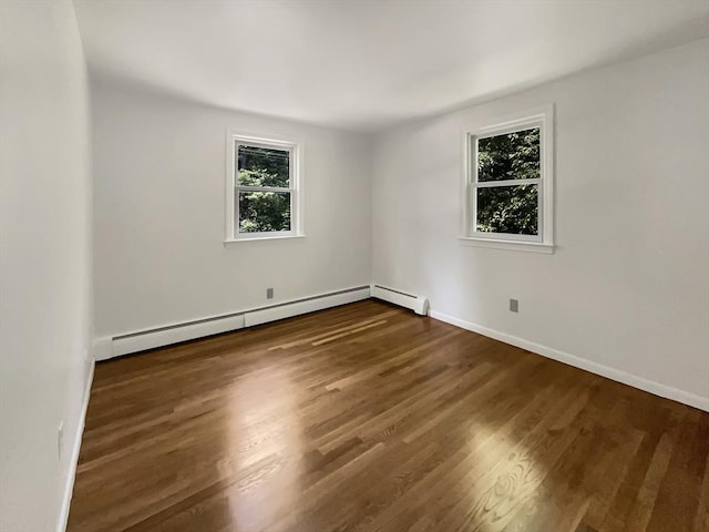 unfurnished room featuring a baseboard heating unit, baseboards, and wood finished floors